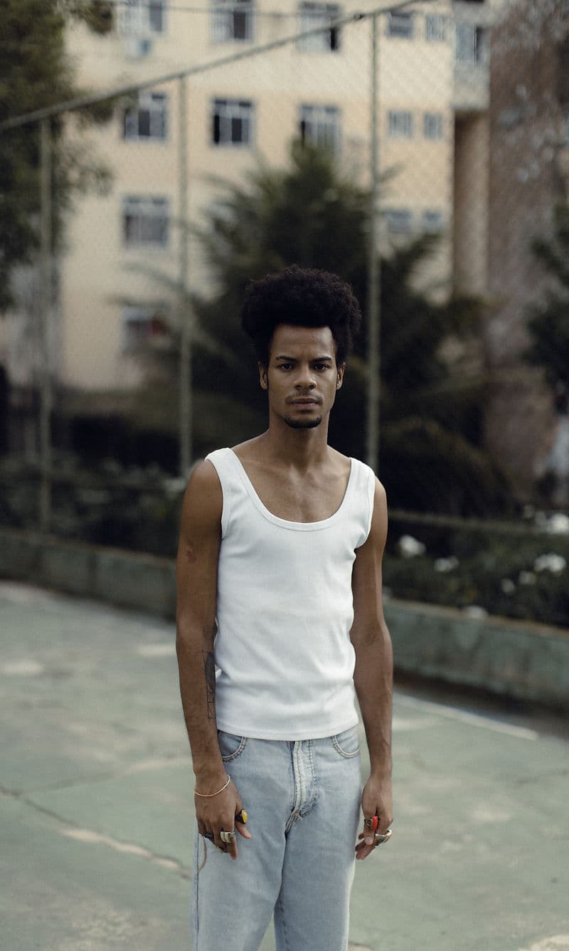 Na foto um homem negro com blackpower de camiseta branca com o fundo borrado